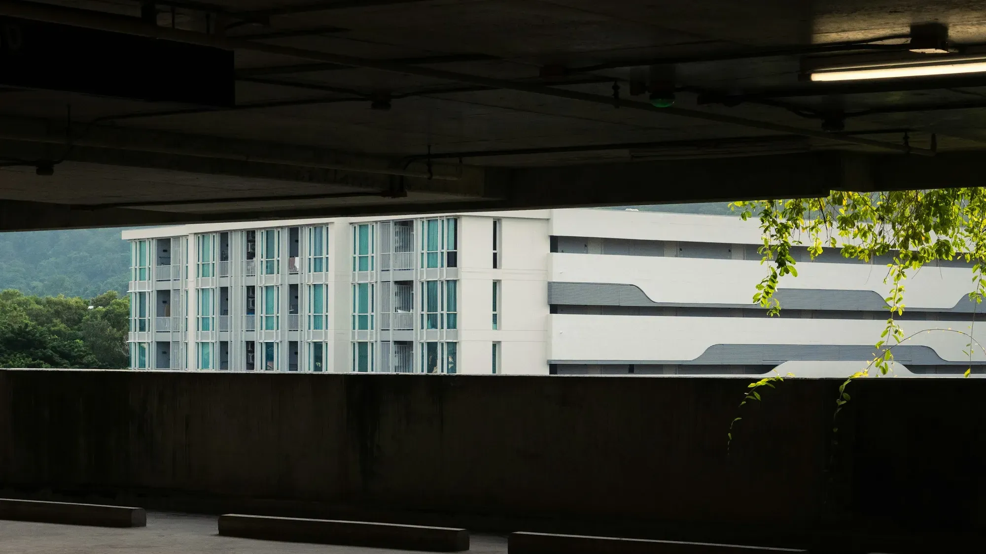 Parqueadero cubierto de concreto con vista a un edificio de apartamentos blanco